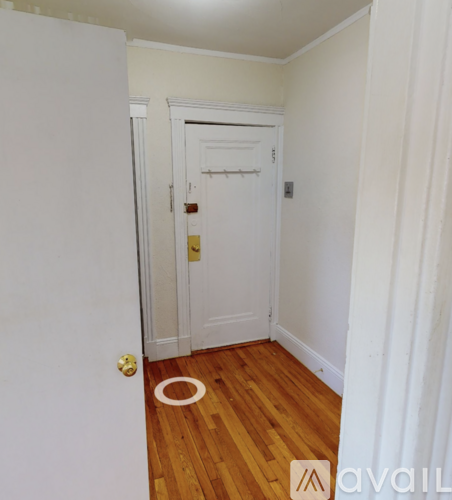 A white door with a gold handle is in a room with wooden floors.
