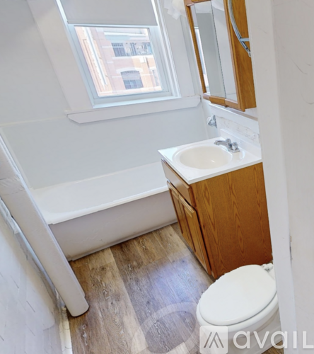 A white toilet sits in a bathroom with a white tub and sink.