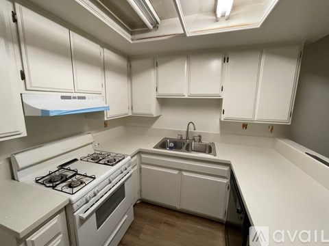 A kitchen with white cabinets and a stove top oven.