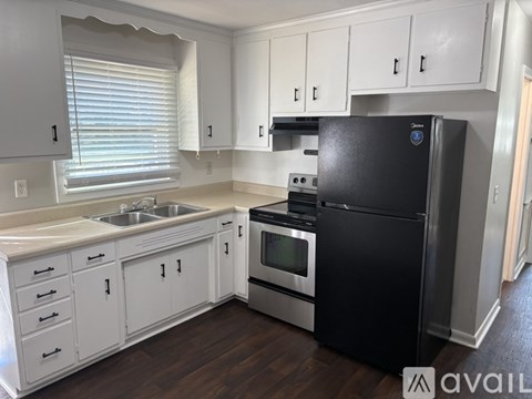 A black fridge in a kitchen with white cabinets.