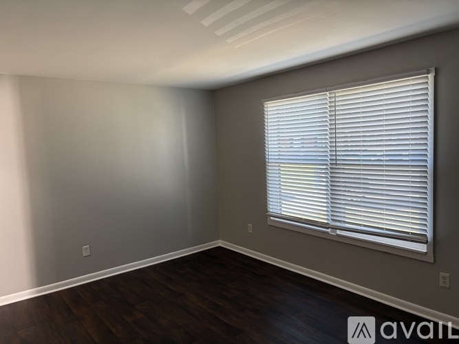 A room with a window covered by white blinds.