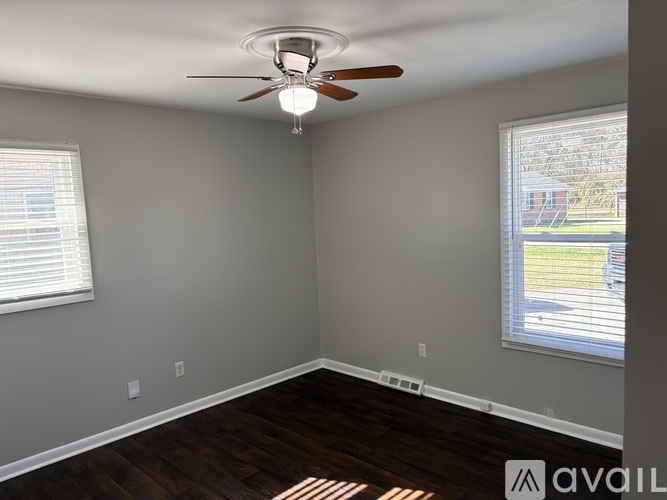 A room with a ceiling fan and a window with blinds.