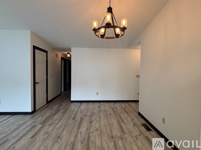 A room with a wooden floor and a chandelier hanging from the ceiling.