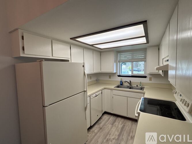 A kitchen with white appliances and cabinets.