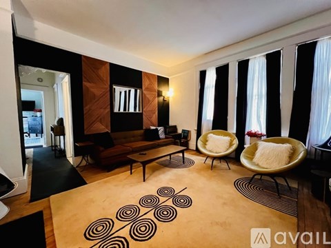 A living room with a brown couch, a chair, and a rug with spiral designs.