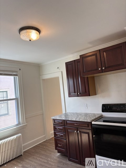 A kitchen with brown cabinets and a white stove top oven.