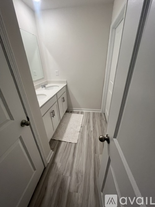 A bathroom with a sink, mirror, and a door with a handle.