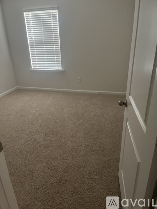 A room with a carpeted floor and a window with blinds.