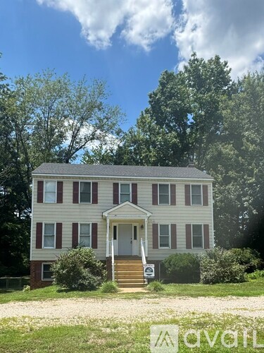 A two-story house with a red brick foundation and a white front porch.