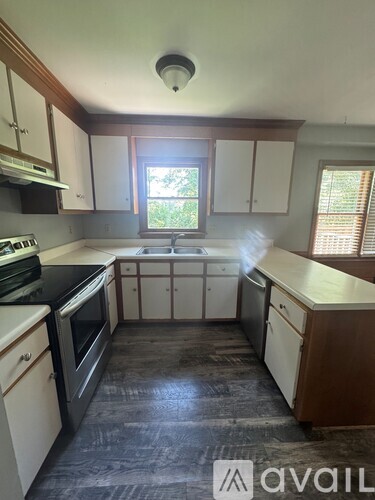 A kitchen with a black stove top oven and a window with blinds.