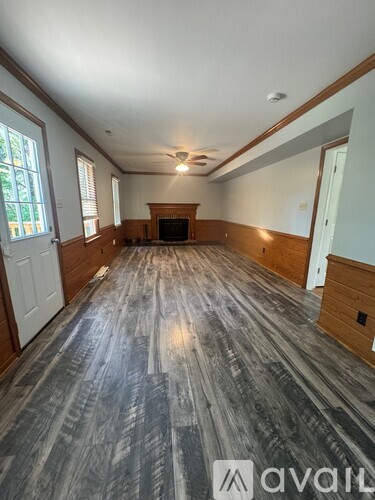 A spacious room with wood flooring and a fireplace.