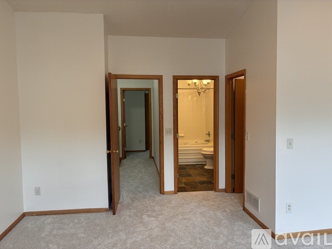 A carpeted hallway with a doorway leading to a bedroom.