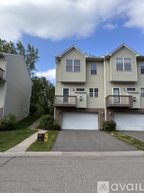 A two-story residential building with a garage and a driveway.