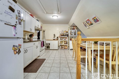 A kitchen with white cabinets and a white fridge with magnets on it.