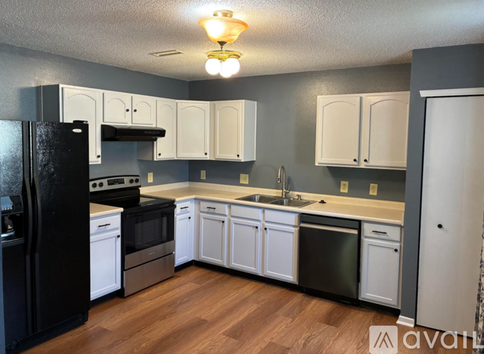 A kitchen with black and white appliances and cabinets.
