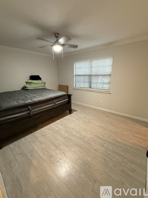 A bedroom with a bed, a ceiling fan, and a window with blinds.
