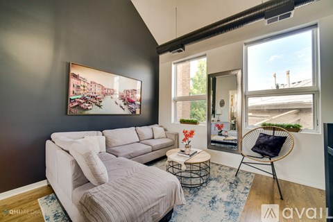 A living room with a grey couch and a painting of a cityscape on the wall.