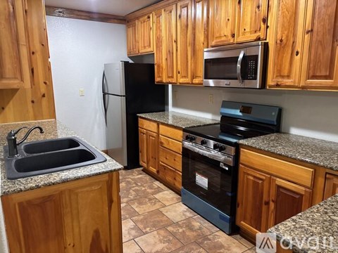 A kitchen with wooden cabinets and a black refrigerator.