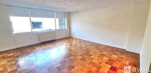 A room with wooden flooring and a window overlooking a building.