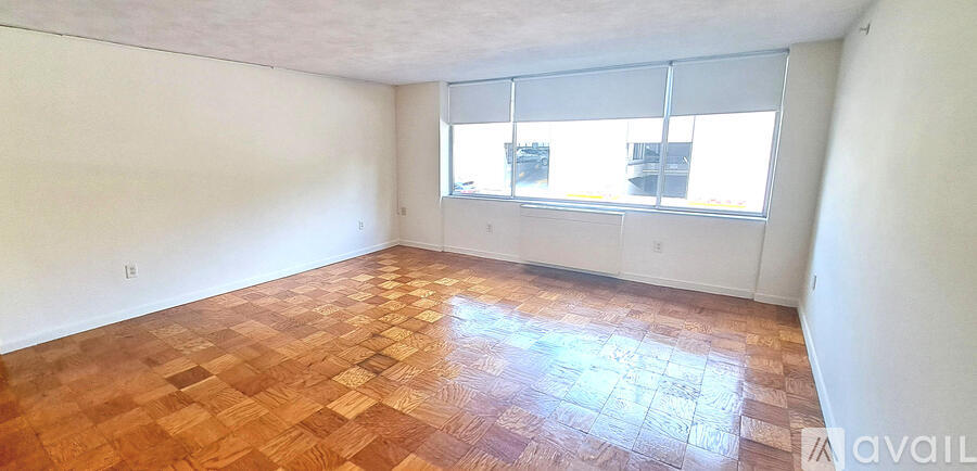 A room with wooden flooring and a window with blinds.
