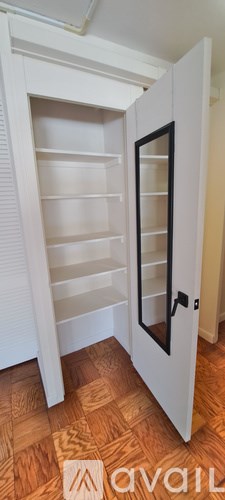 A white pantry with a door open to a kitchen.