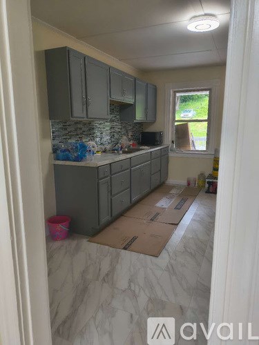 A kitchen with grey cabinets and a window.