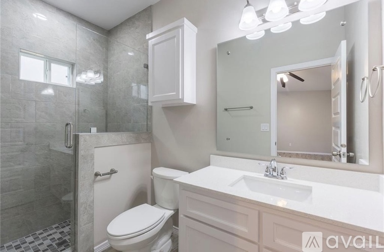 A bathroom with a toilet, sink, and mirror.