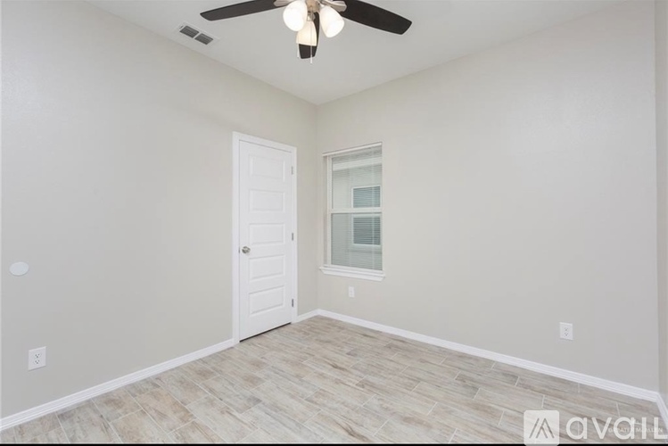 A room with a ceiling fan and a door leading to a balcony.