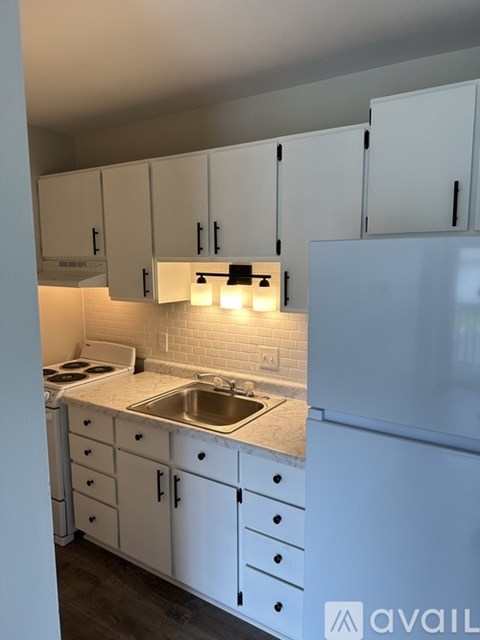 A kitchen with white cabinets and a white refrigerator.