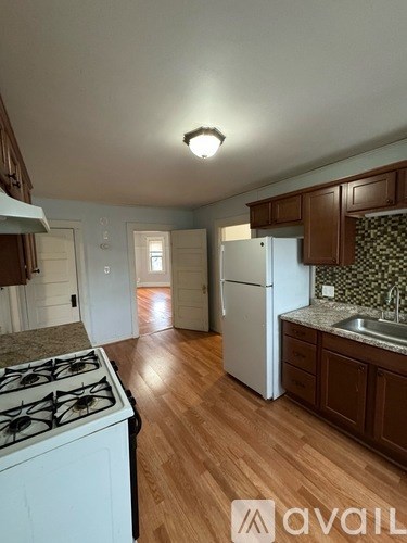 A kitchen with a white stove and wooden floors.