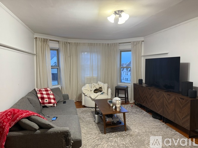 A living room with a grey couch, a white armchair, a wooden coffee table, and a television.