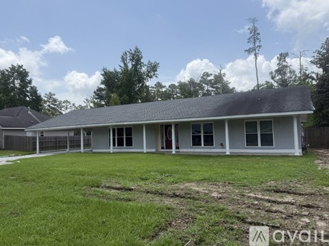A house with a grey roof and white walls is surrounded by a grassy area.