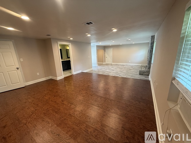 A spacious room with wooden flooring and white walls.