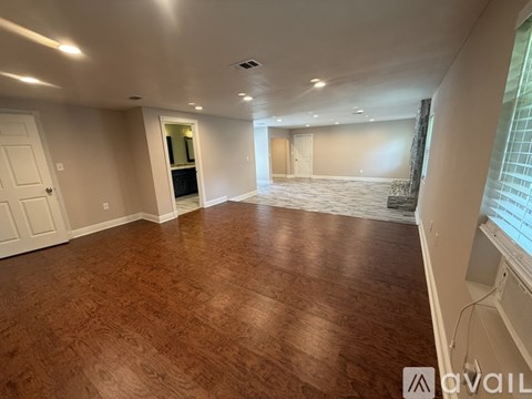 A spacious room with wooden flooring and white walls.