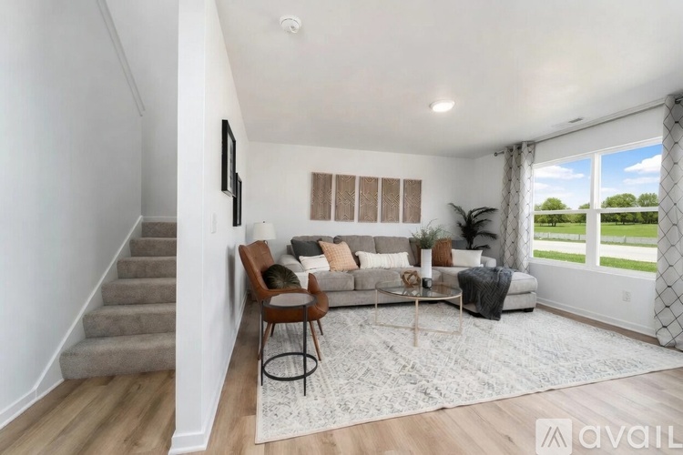 A living room with a staircase on the left and a couch with a coffee table in front of it.