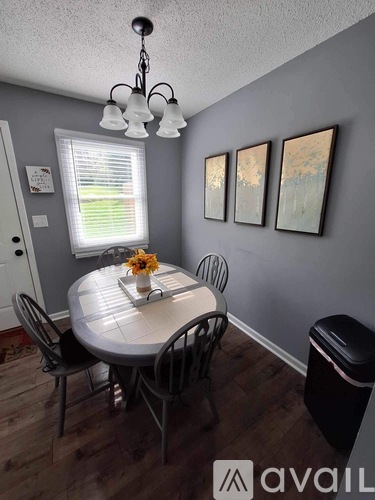 A dining room with a table set for four and a chandelier.