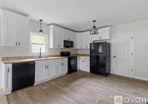 A kitchen with black appliances and white cabinets.
