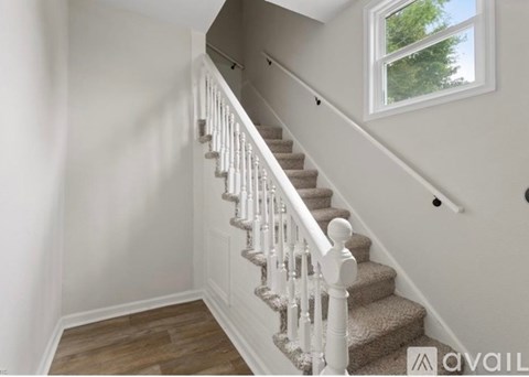A staircase with a beige carpet and white balusters.