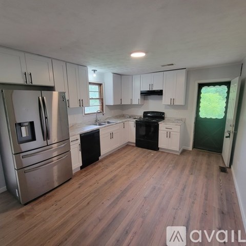 A kitchen with wooden floors and white cabinets.