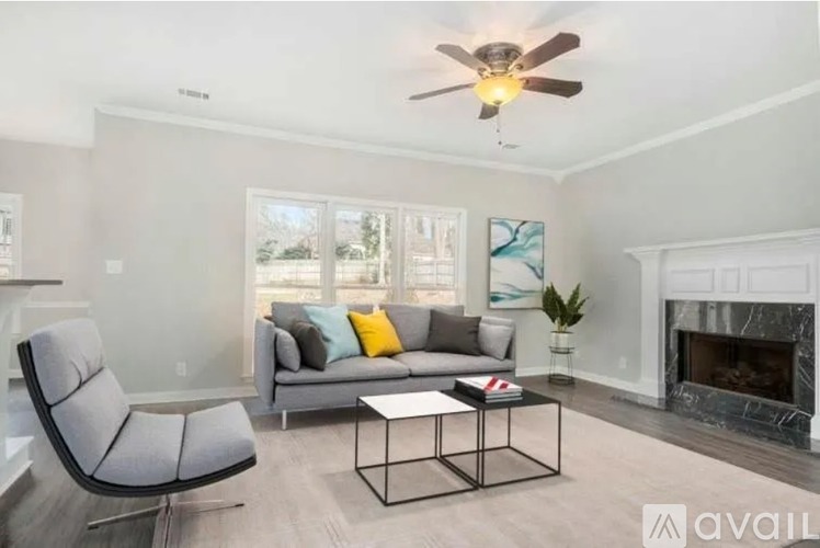 A living room with a grey couch, a black chair, a coffee table, and a fireplace.