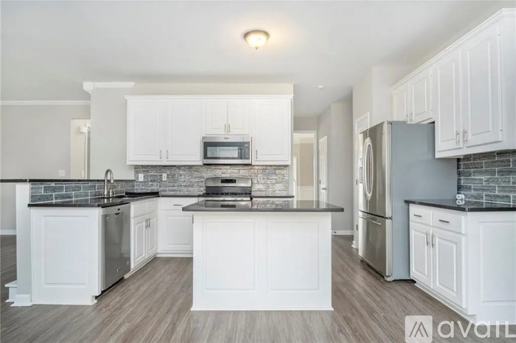 A kitchen with white cabinets and a black countertop.