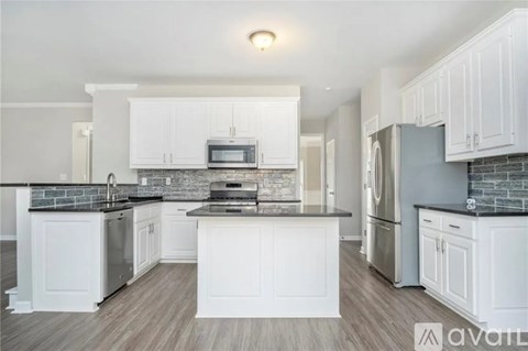 A kitchen with white cabinets and a black countertop.