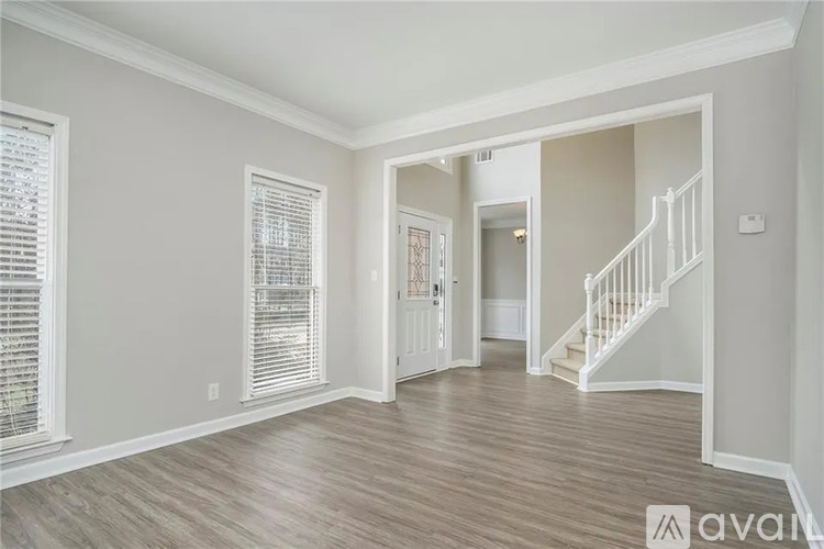 A spacious room with wooden flooring and a staircase leading to another room.