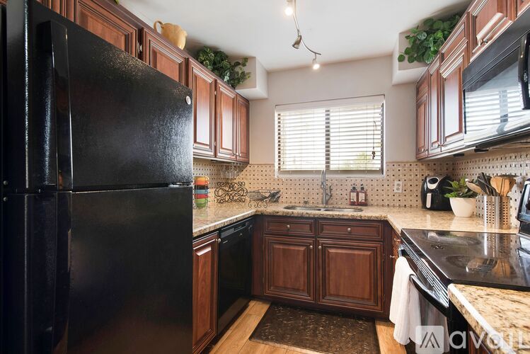 A kitchen with a black refrigerator and wooden cabinets.