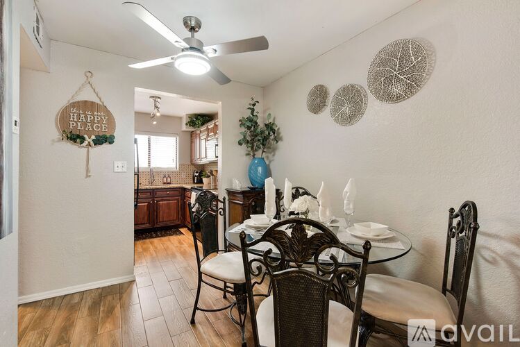 A dining room with a table set for two and a ceiling fan.