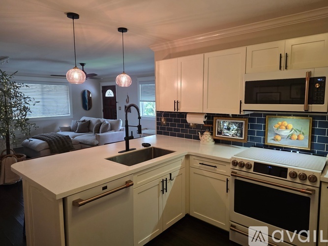 A kitchen with a white countertop and a stove with a pot on it.