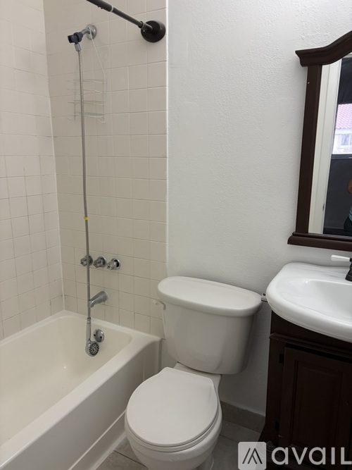 A white toilet is in a bathroom with a white tub and sink.