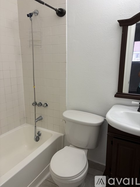 A white toilet is in a bathroom with a white tub and sink.