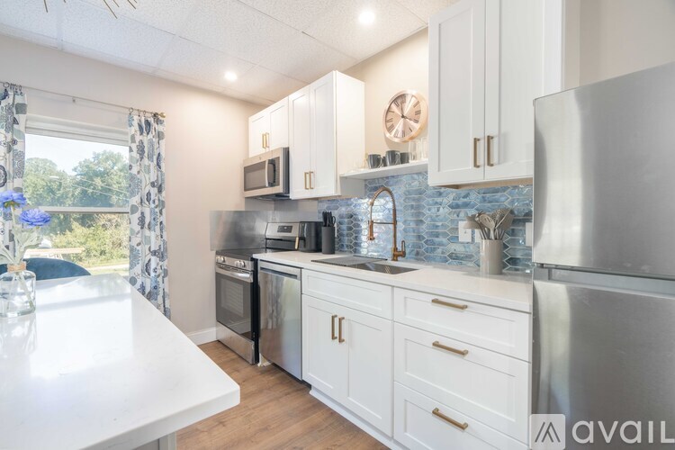 A kitchen with white cabinets and a blue tile backsplash.