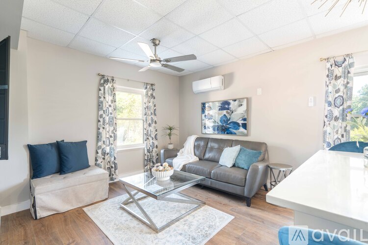 A living room with a grey couch, a white coffee table, and a painting on the wall.